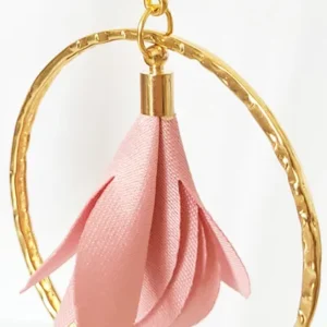 Boucles d'oreilles pendantes avec des supports en formes de 3 coeurs colorés en prune nacrée et dorés. Ces supports ont un anneau martelé et un pompon en imitation satin de couleur rose à l'intérieur.