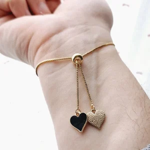 Bracelet réglable avec un coeur doré noir en pixel et des pampilles en forme de coeurs noirs et dorés